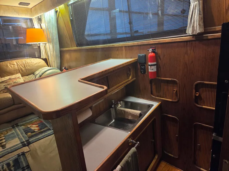 Slide: The Image of 1989 Chris-Craft 42 Sportfish Commander interior with kitchenette, sink, and cozy seating area. - 39