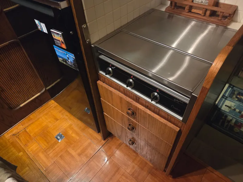 Slide: The Image of 1989 Chris-Craft 42 Sportfish Commander kitchen with stainless steel stove and wooden cabinetry. - 43