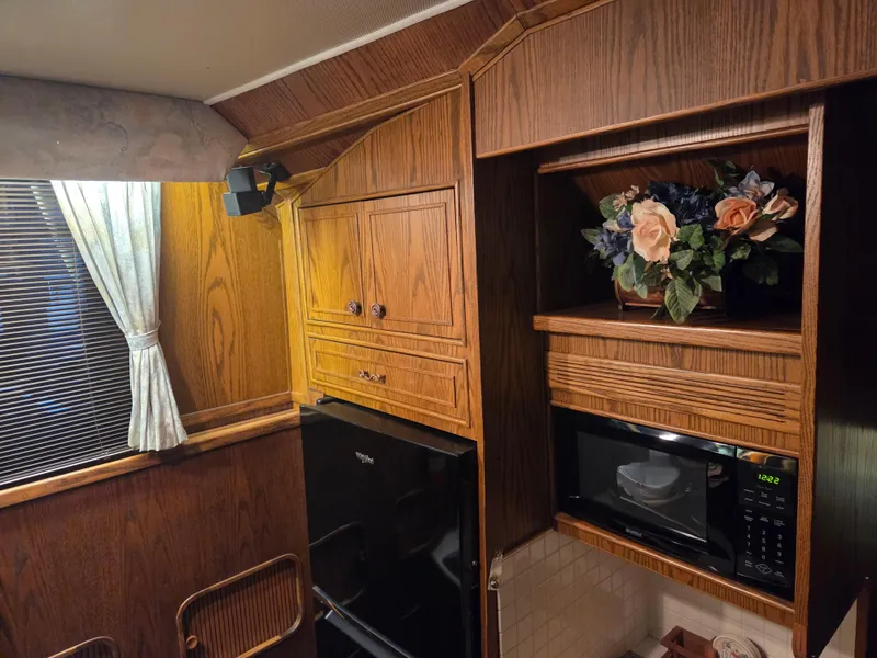 Slide: The Image of 1989 Chris-Craft 42 Commander Sportfish interior with wood cabinetry, microwave, and floral decor. - 46