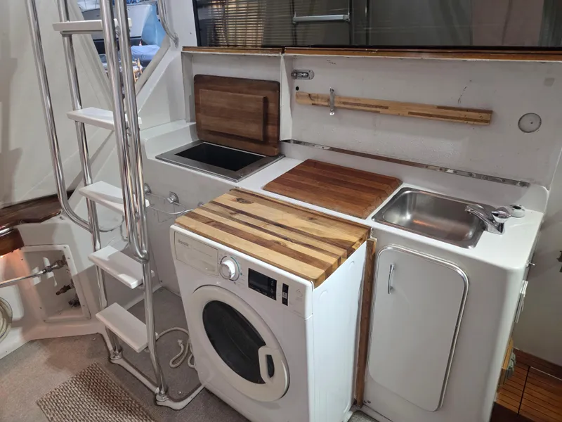 Slide: The Image of Laundry area on 1989 Chris-Craft 42 Sportfish Commander with washer, sink, and wooden countertops. - 72