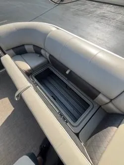 Slide: The Image of 2023 Sun Tracker Party Barge 20 DLX with open storage compartment on cushioned seating. - 9