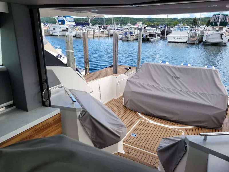 Slide: The Image of 2021 Tiara Sport 43LE yacht docked at marina, featuring covered seating and wooden deck. - 15