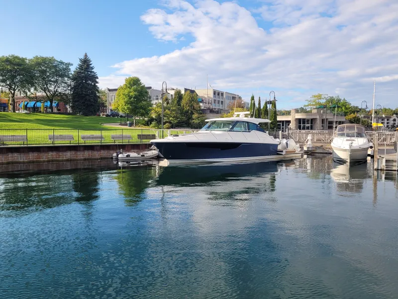 Slide: The Image of 2021 Tiara Sport 43LE yacht docked in a scenic marina with lush greenery. - 47