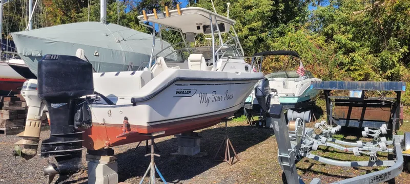 Slide: The Image of 1999 Boston Whaler 23 Conquest boat on dry dock with trailer nearby. - 6