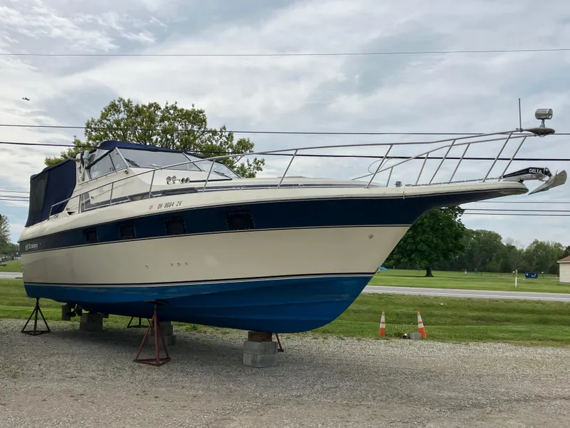 Slide: The Image of 1985 Cruisers 336 Ultra Vee boat on stands, blue and white hull, outdoor setting. - 0