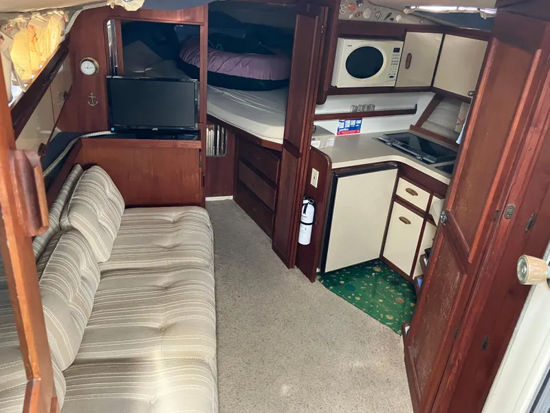 Slide: The Image of Interior of 1985 Cruisers 336 Ultra Vee boat with sofa, kitchenette, and sleeping area. - 16