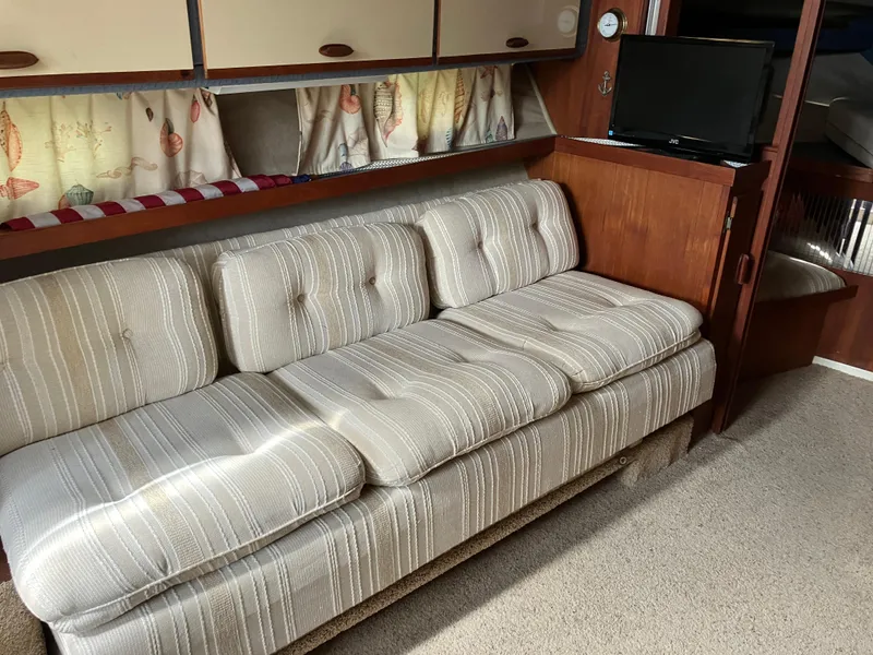 Slide: The Image of 1985 Cruisers 336 Ultra Vee interior with striped sofa, wooden cabinets, and small TV. - 19