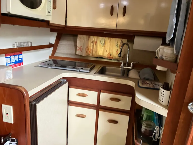 Slide: The Image of 1985 Cruisers 336 Ultra Vee boat kitchen with sink, stove, and storage cabinets. - 23