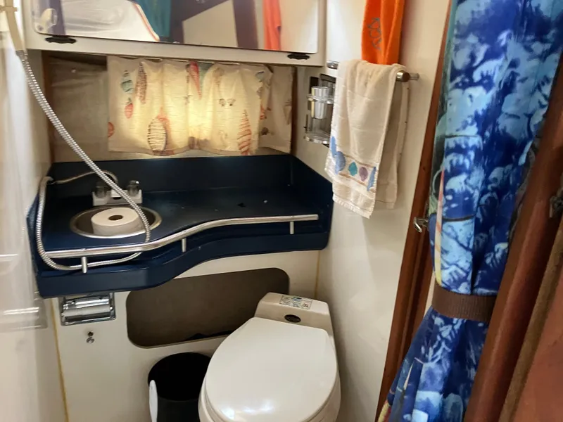 Slide: The Image of 1985 Cruisers 336 Ultra Vee boat bathroom with sink, toilet, and shower curtain. - 29
