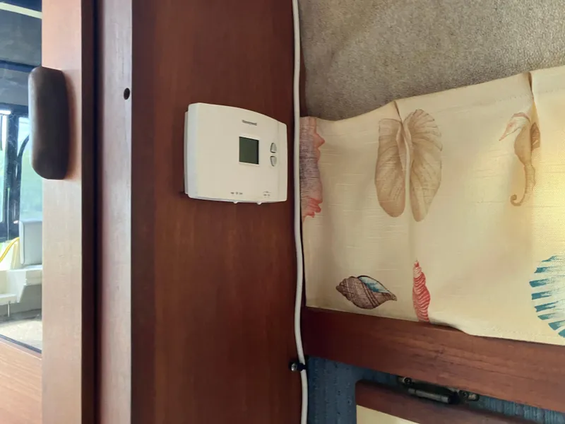 Slide: The Image of Thermostat on wooden panel inside 1985 Cruisers 336 Ultra Vee boat, near decorative curtain. - 32