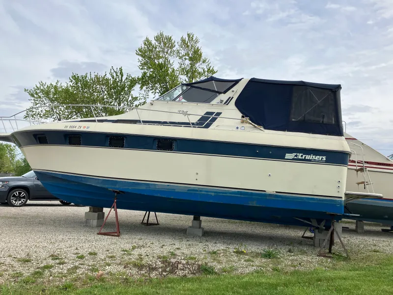 Slide: The Image of 1985 Cruisers 336 Ultra Vee boat on stands, outdoors, with blue and white design. - 4