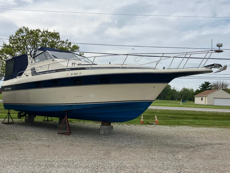 Slide: The Image of 1985 Cruisers 336 Ultra Vee boat on stands, parked outdoors on gravel. - 7
