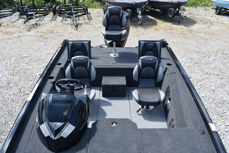 Slide: The Image of 2025 Lund 1875 Renegade SS boat interior with seating and steering console on gravel lot. - 13