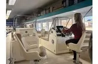 Slide: The Image of 2025 Scout 195 Sport Dorado interior with person at helm in showroom. - 3