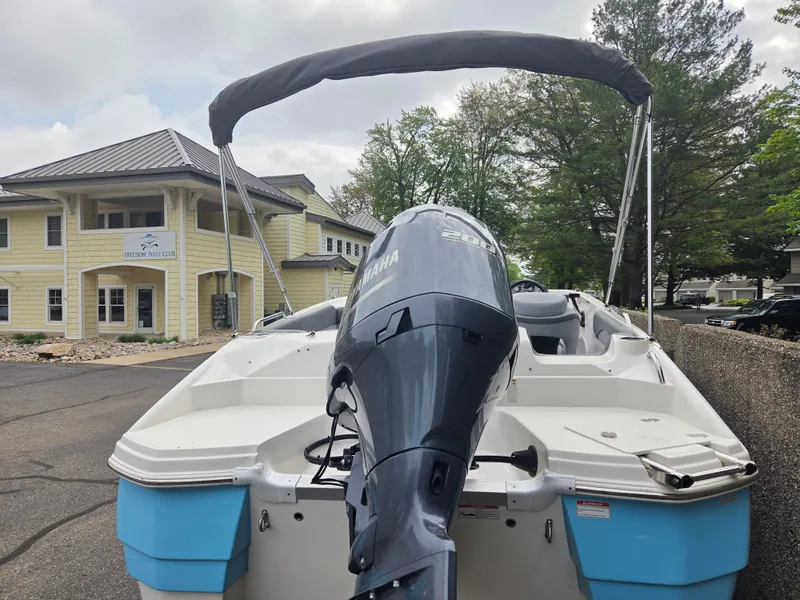 Slide: The Image of 2023 NauticStar 203DC boat with Yamaha engine, parked near a yellow building. - 3