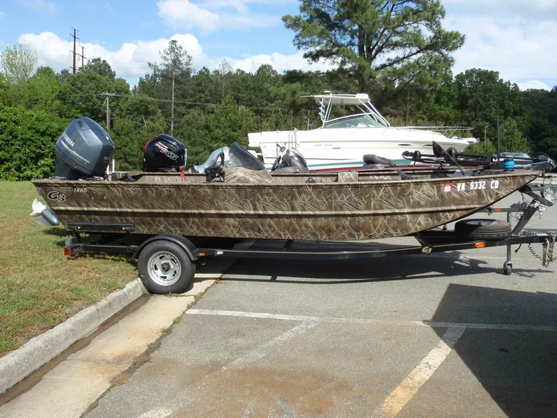 Slide: The Image of 2013 G3 1860 SC boat on trailer, parked outdoors with trees in background. - 3