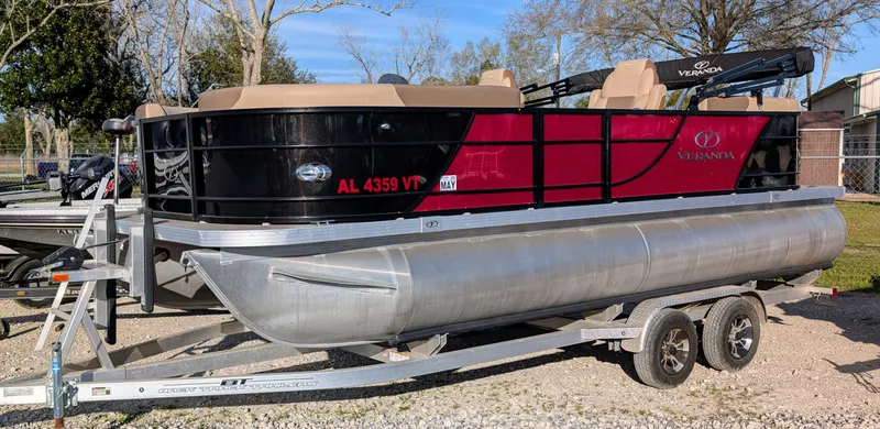 Slide: The Image of 2023 Veranda VR20RC pontoon boat on trailer, red and black design, parked outdoors. - 1
