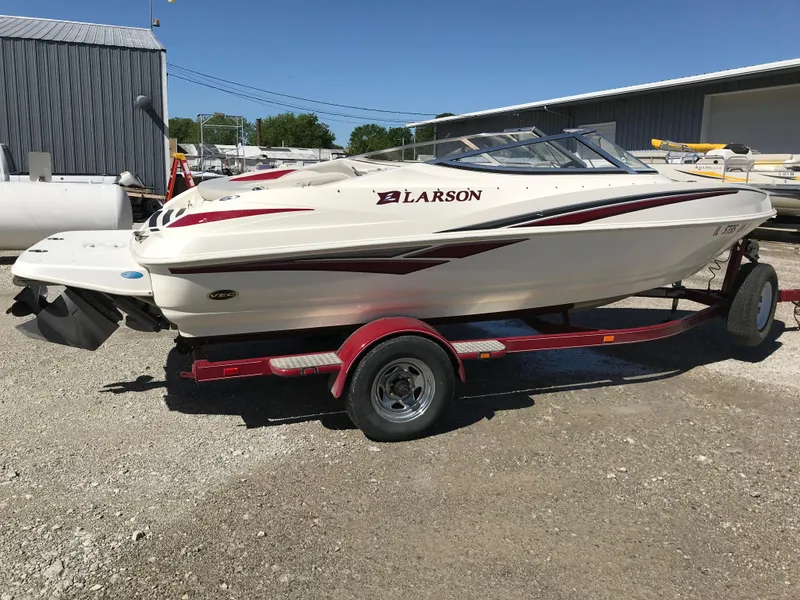 Slide: The Image of 2005 Larson Senza 186 I/O boat on a red trailer, parked outdoors. - 1