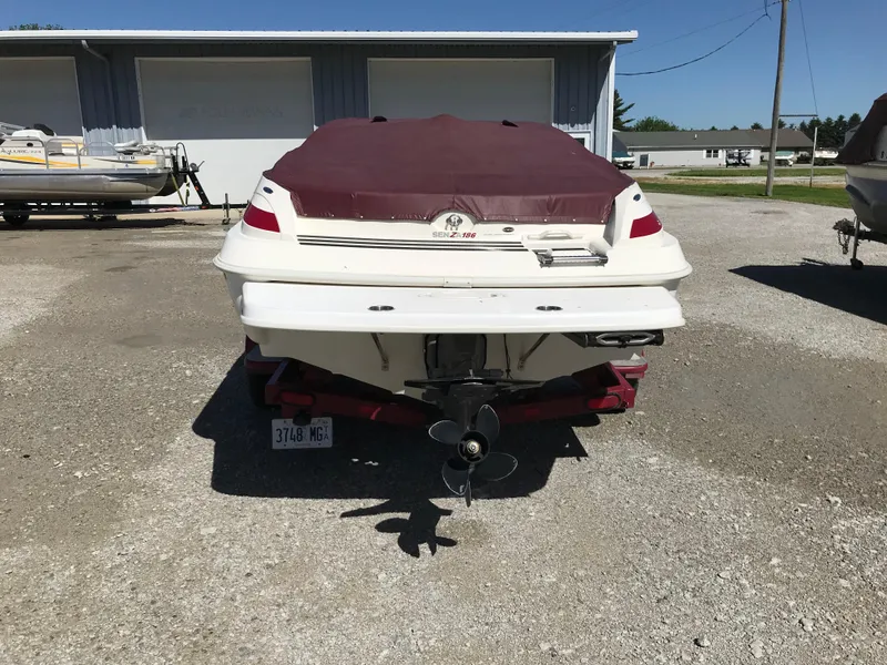Slide: The Image of 2005 Larson Senza 186 I/O boat, covered, parked on gravel near a building. - 31