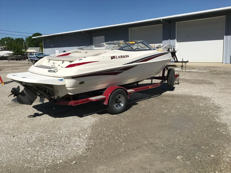 Slide: The Image of 2005 Larson Senza 186 I/O boat on trailer, parked outdoors near a warehouse. - 4