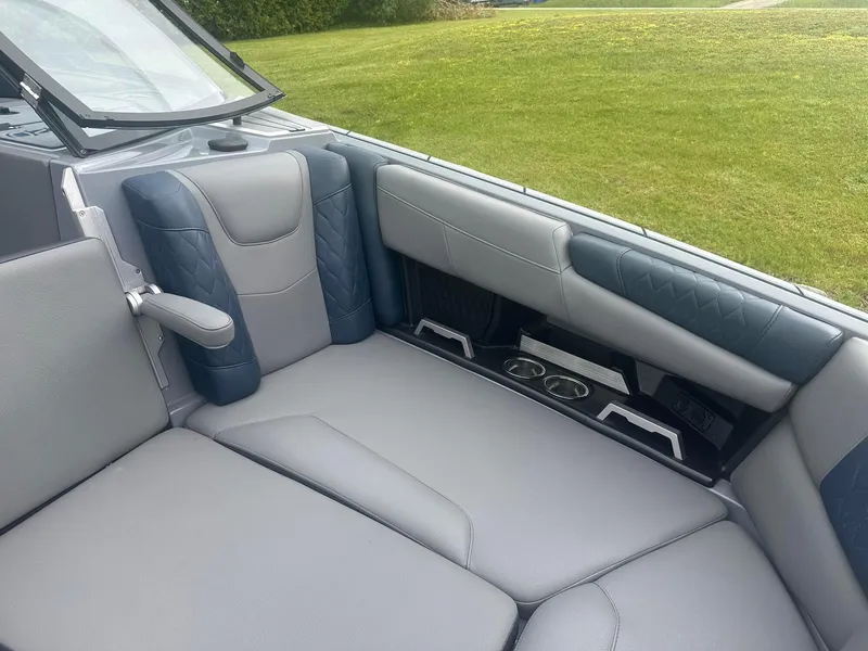 Slide: The Image of 2022 Malibu M220 boat interior with gray and blue seating, cup holders, and armrest. - 14