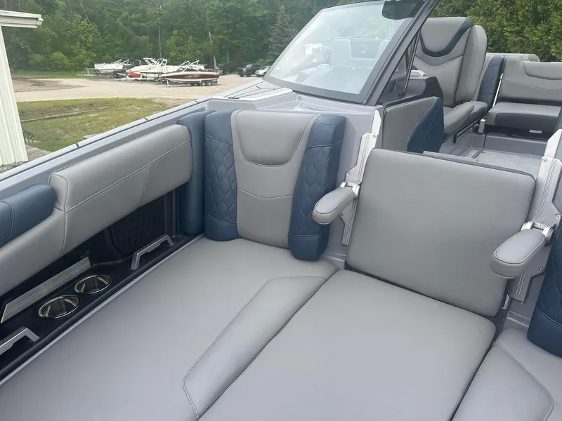 Slide: The Image of 2022 Malibu M220 boat interior with gray and blue seating, cup holders, and armrests. - 15