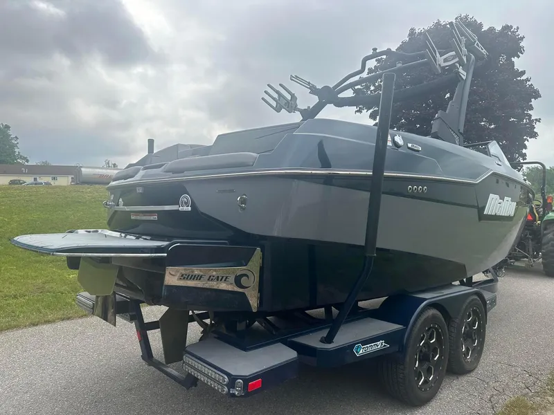 Slide: The Image of 2022 Malibu M220 boat on trailer, featuring Surf Gate technology, parked outdoors. - 7