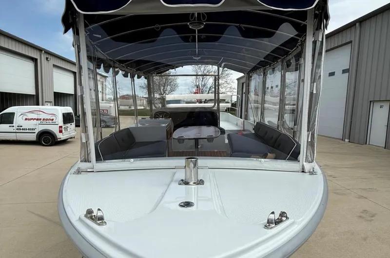 Slide: The Image of 2022 Duffy 22 Sun Cruiser boat with covered seating, docked near industrial buildings. - 1