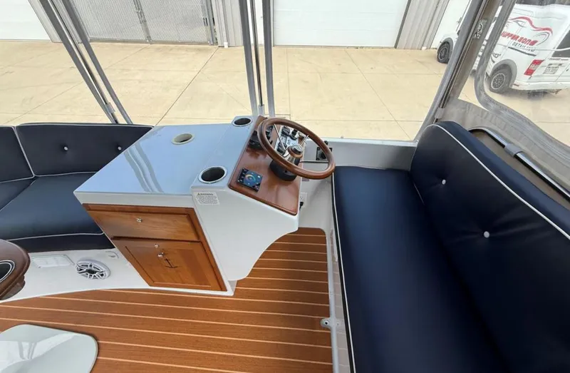 Slide: The Image of 2022 Duffy 22 Sun Cruiser interior with steering wheel, seating, and wooden accents. - 10