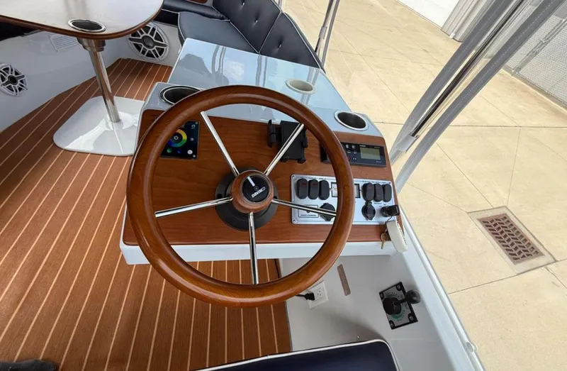 Slide: The Image of 2022 Duffy 22 Sun Cruiser helm with wooden steering wheel and control panel. - 13