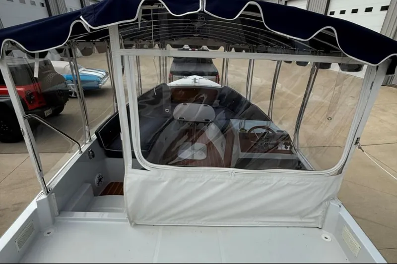 Slide: The Image of 2022 Duffy 22 Sun Cruiser boat with canopy and clear enclosure in a garage setting. - 5