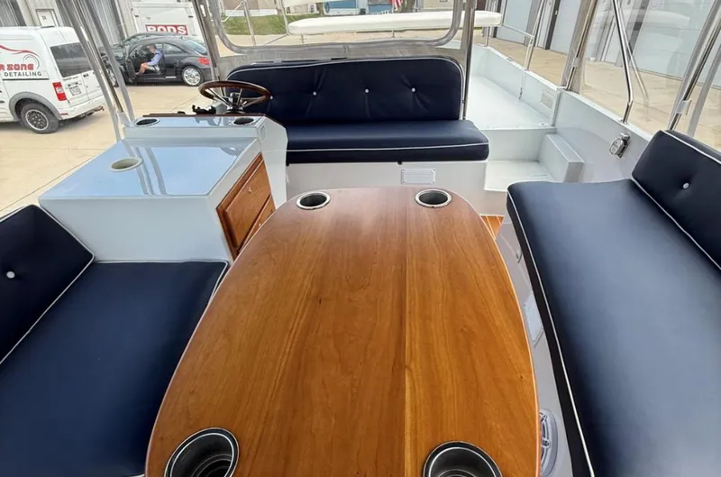 Slide: The Image of Interior of 2022 Duffy 22 Sun Cruiser with wooden table and navy seating. - 9