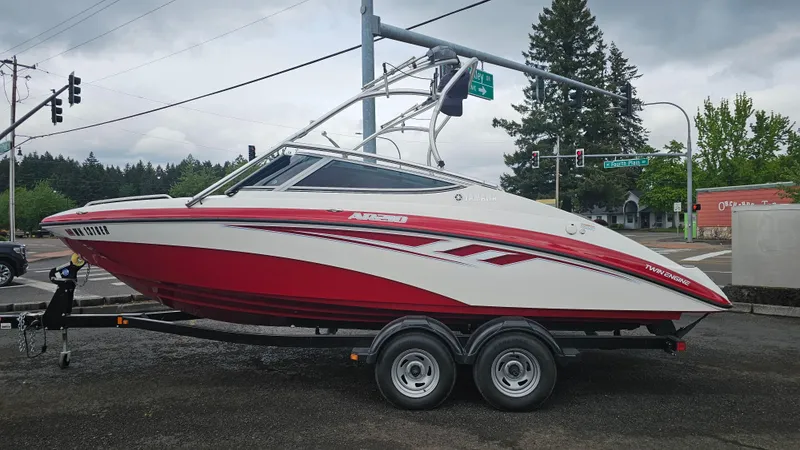 The Image of 2014 Yamaha AR210 boat in red and white on a trailer, parked outdoors. - 0