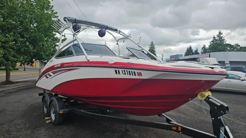 Slide: The Image of 2014 Yamaha AR210 boat in red and white on a trailer, parked outdoors. - 3