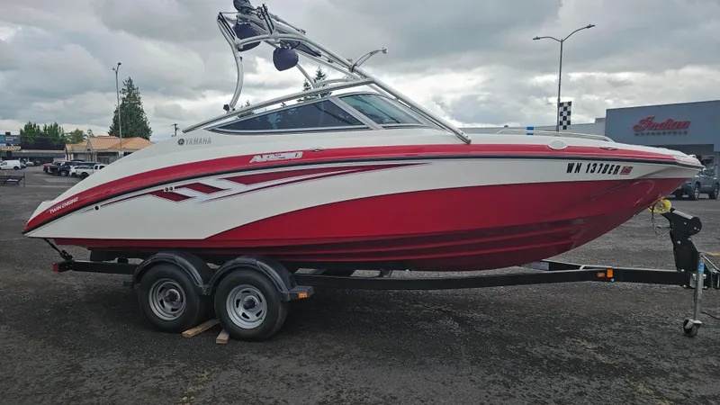 Slide: The Image of 2014 Yamaha Boats AR210 on trailer, red and white design, parked outdoors. - 4