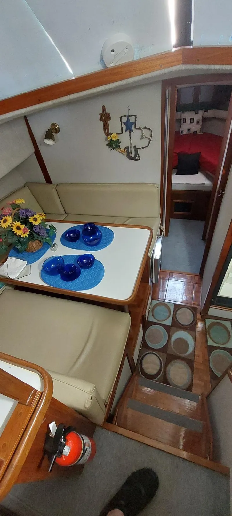 Slide: The Image of 1990 Carver 3607 Aft Cabin interior with dining area, blue tableware, and cozy seating. - 3