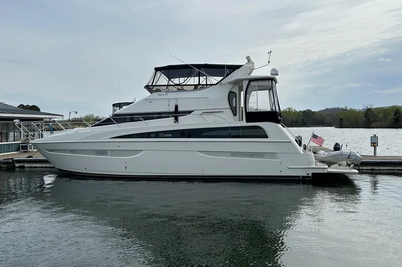 The Image of 2006 Carver 43 Motor Yacht docked on a calm lake under a cloudy sky. - 0