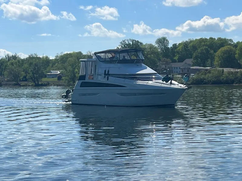 Slide: The Image of 2006 Carver 43 Motor Yacht cruising on a serene lake under a clear blue sky. - 2