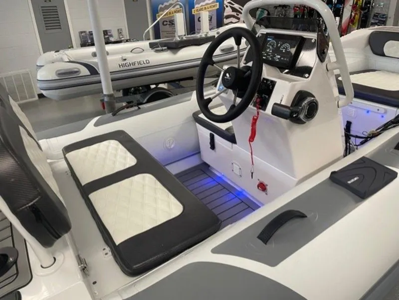 Slide: The Image of 2025 Highfield Sport 390 boat interior with steering wheel and seating, showroom display. - 2