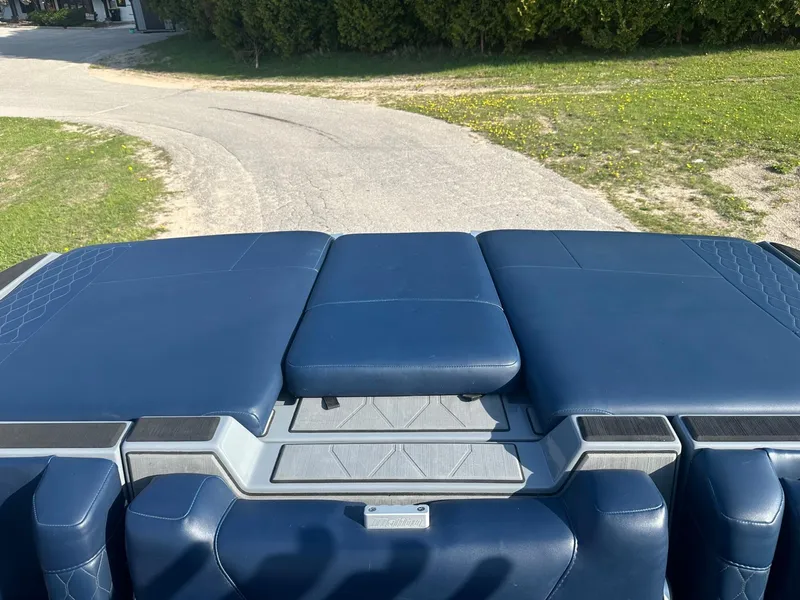 Slide: The Image of 2020 Malibu M240 boat with blue seating, viewed from the rear on a sunny day. - 14