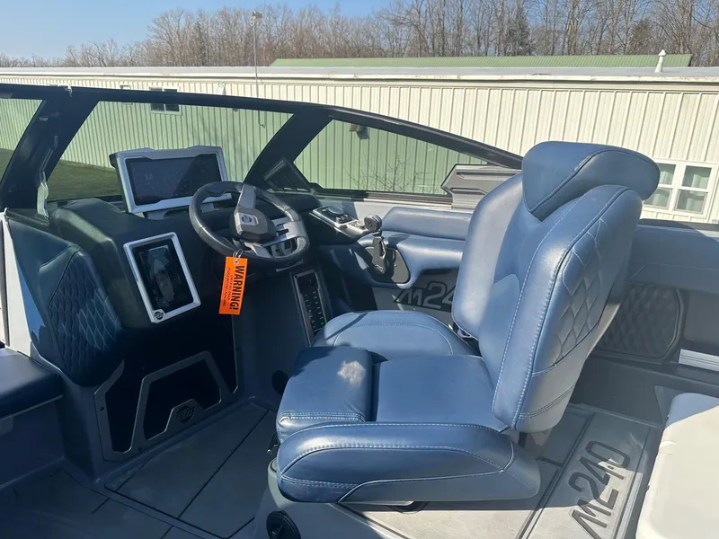 Slide: The Image of 2020 Malibu M240 boat interior with blue captain's seat and modern dashboard. - 15