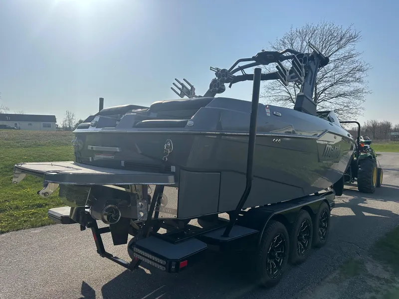 Slide: The Image of 2020 Malibu M240 boat on trailer, parked outdoors under clear sky. - 3