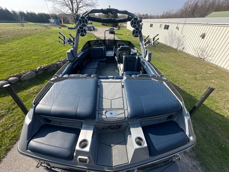 Slide: The Image of 2020 Malibu M240 boat with spacious seating and modern design, parked outdoors. - 5