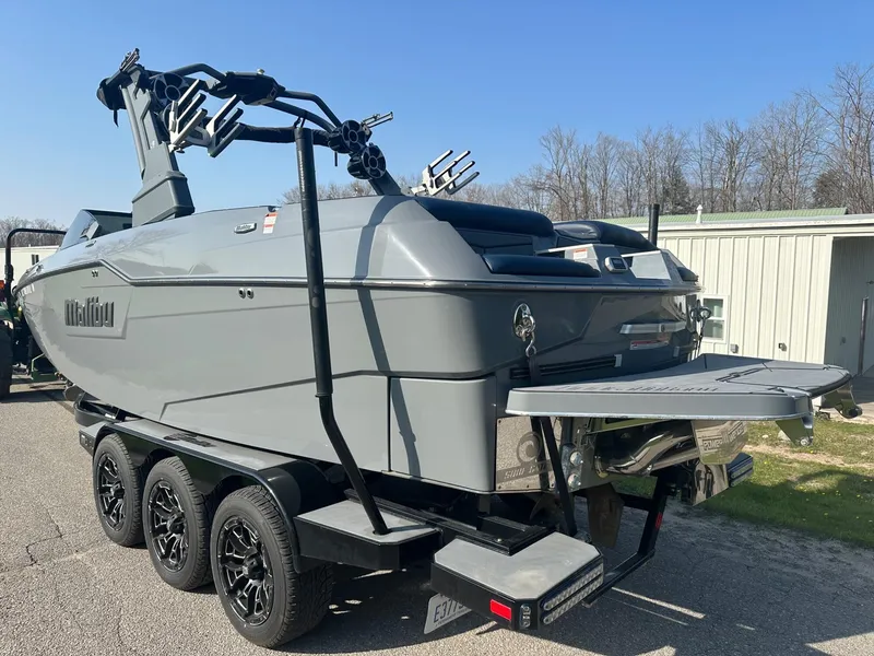 Slide: The Image of 2020 Malibu M240 boat on trailer, gray exterior, parked outdoors. - 6