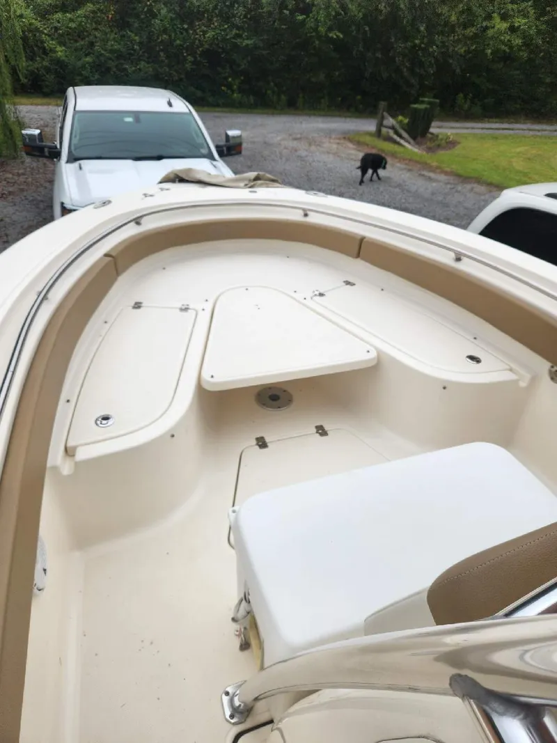 Slide: The Image of 2019 Pioneer 222 Sportfish boat, beige interior, parked near vehicles and greenery. - 7