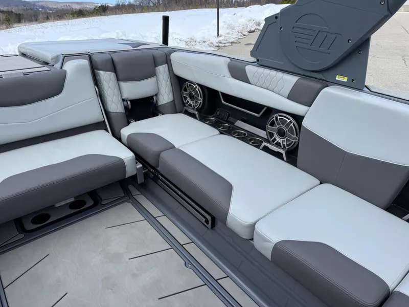 Slide: The Image of 2021 Malibu M240 boat interior with gray seating and built-in speakers. - 14