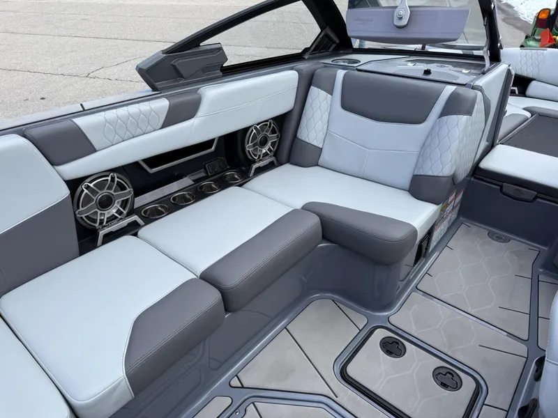 Slide: The Image of 2021 Malibu M240 boat interior with gray and white seating, featuring premium speakers and cup holders. - 15