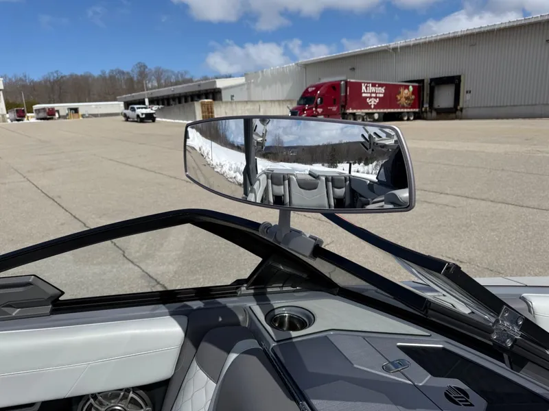 Slide: The Image of 2021 Malibu M240 boat interior with rearview mirror, parked near industrial buildings. - 32