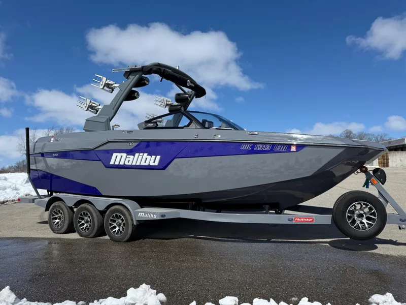 Slide: The Image of 2021 Malibu M240 boat on trailer under clear blue sky. - 33