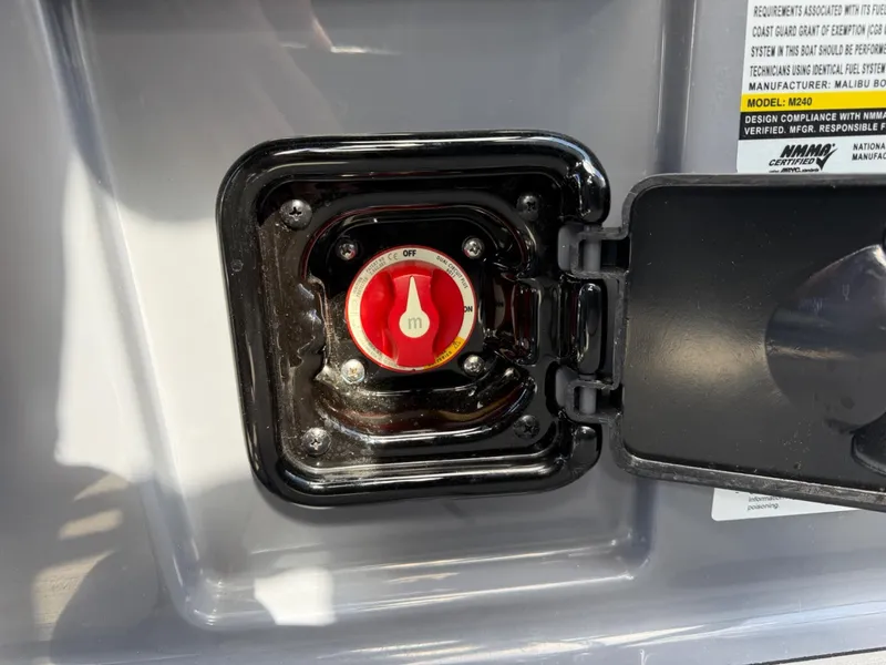Slide: The Image of 2021 Malibu M240 battery switch compartment with red dial and protective cover. - 34